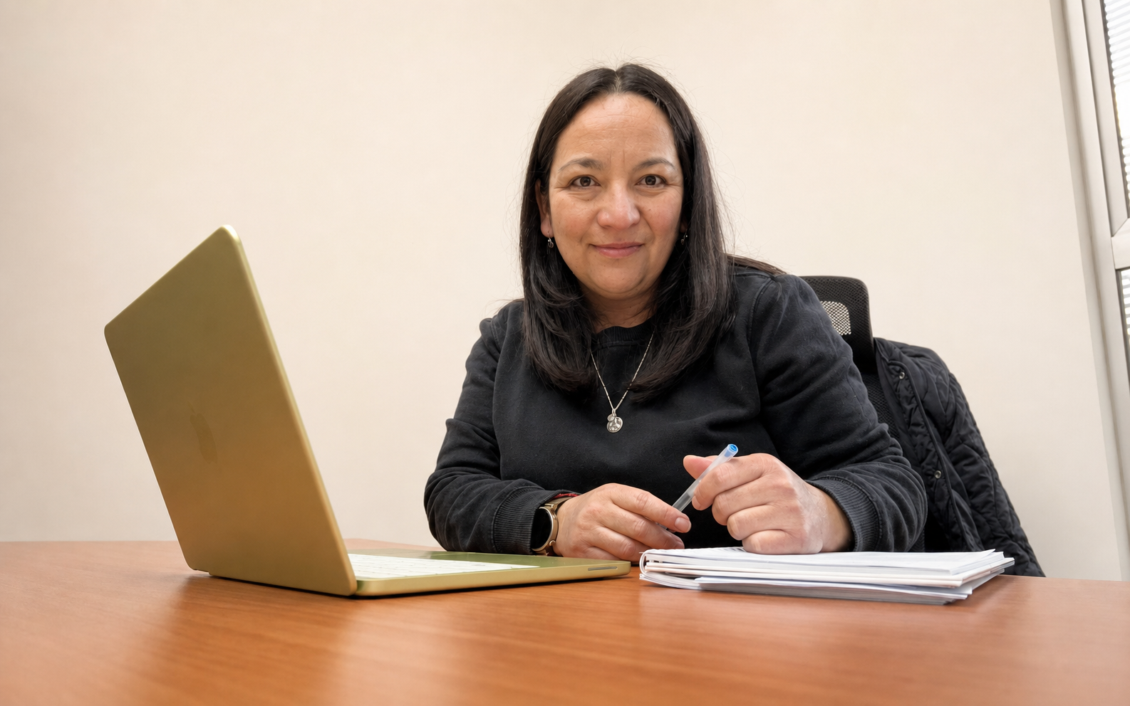 Gaby trabajando en su escritorio con un computador y un cuaderno